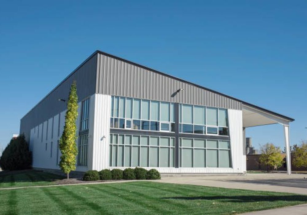 Modern building in gray and white aluminum siding and flat angled roofline and front windows.
